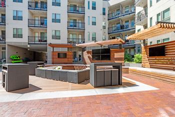 A modern outdoor seating area with wooden and concrete furniture.